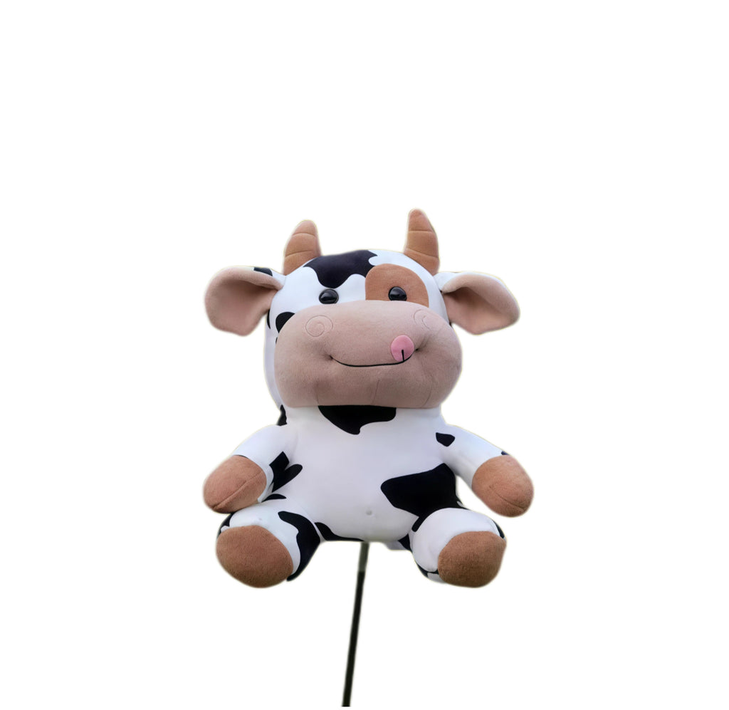 Front view of cow plush golf headcover, black-spotted body with tan horns, pink tongue and embroidered swirl cheeks