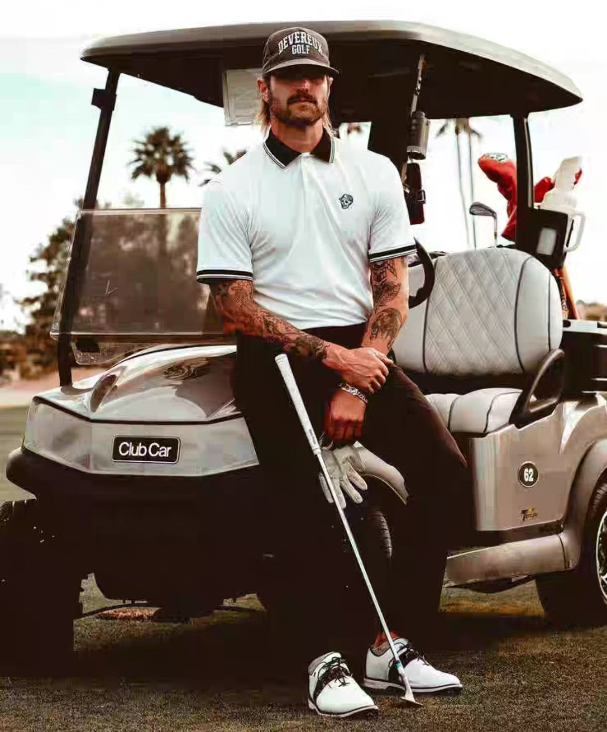 Devereux men’s White letter-print golf polo full-length model view beside golf cart