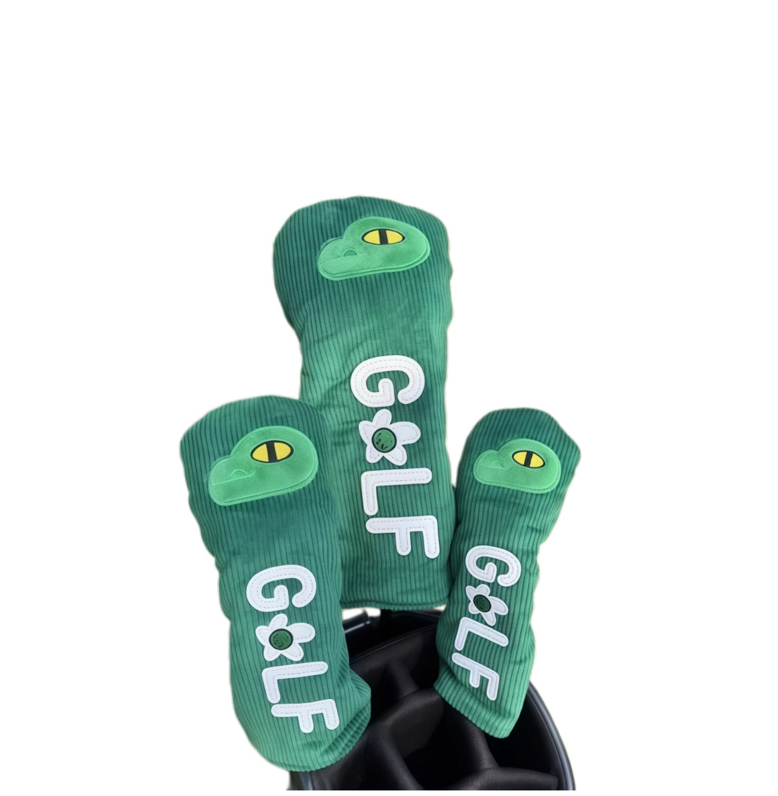 Green corduroy golf headcovers set with embroidered dinosaur eye and “GOLF” letters, designed for driver, fairway and utility clubs with durable, cute protection.