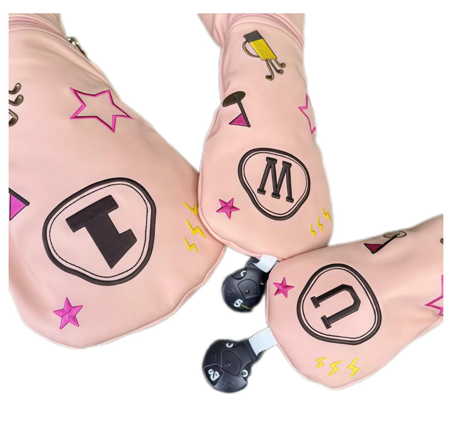 Close-up of pink cartoon puppy golf headcovers showing embroidered “1”, “W”, “U” labels, stars, lightning bolts and golf bag图案, highlighting precise stitching and playful design.
