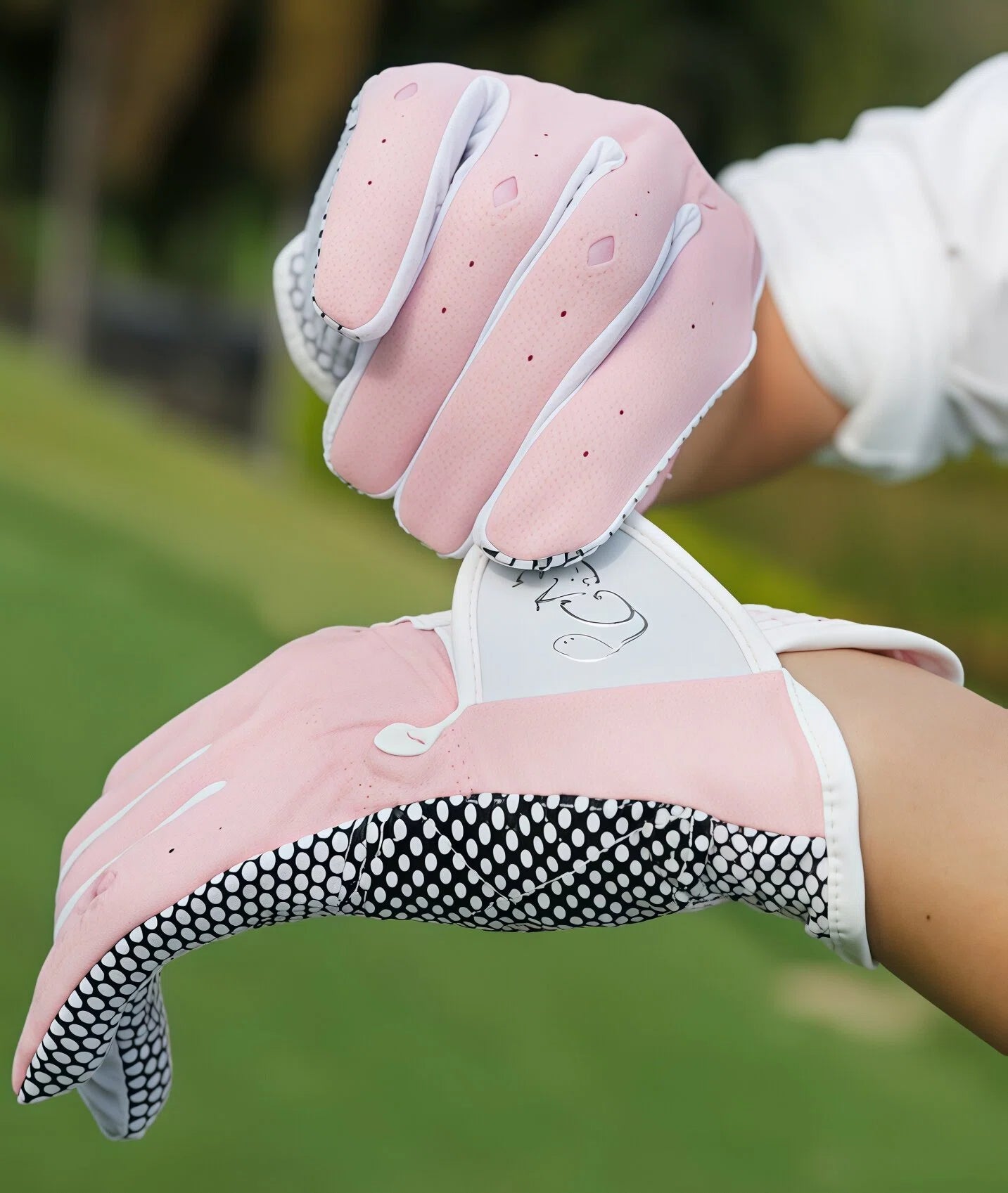 A model's hand wearing the pink PGM women's golf glove, showcasing its flexibility and comfortable fit. The image highlights the glove's breathable fabric and ergonomic design that moves with the hand.