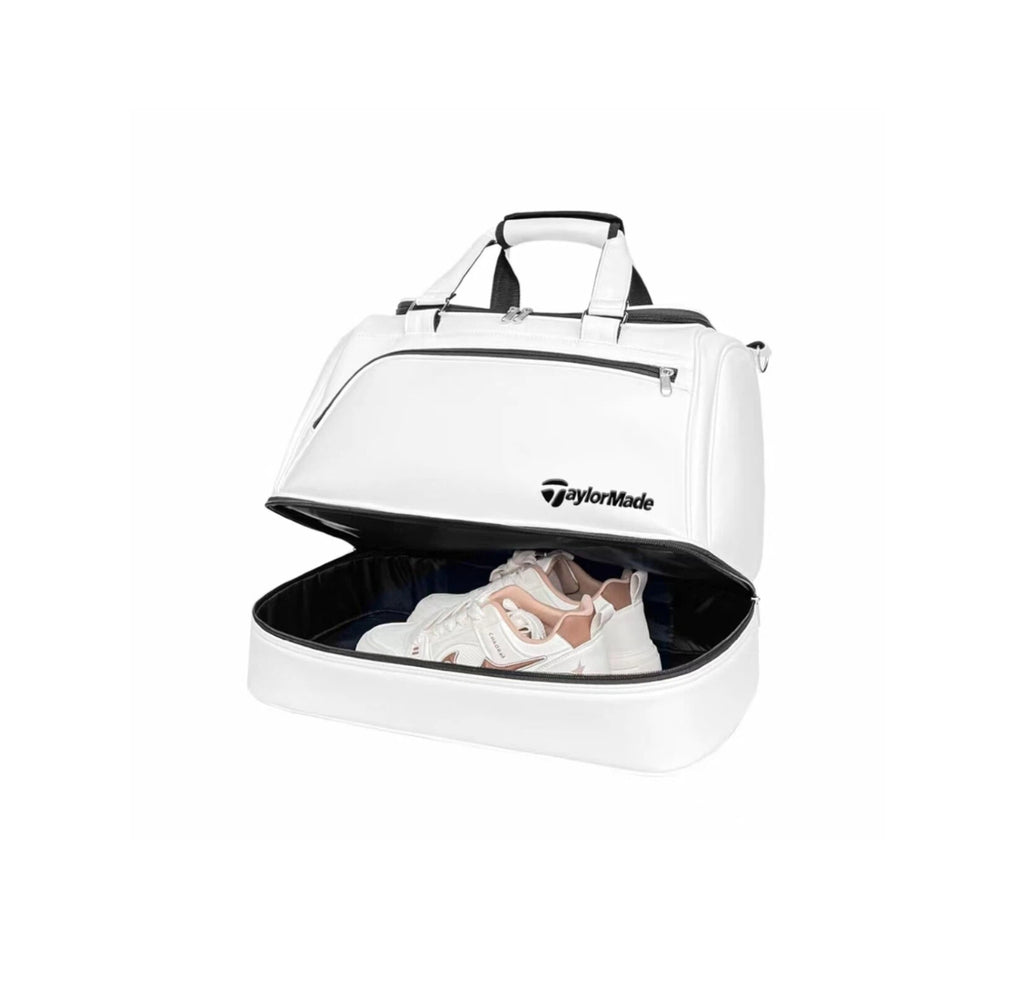 White TaylorMade TM24 Authentic Boston bag with the lower shoe compartment open, displaying a pair of white athletic shoes. The spacious, ventilated shoe section keeps footwear separated from clothes, ideal for golfers and athletes on the go.
